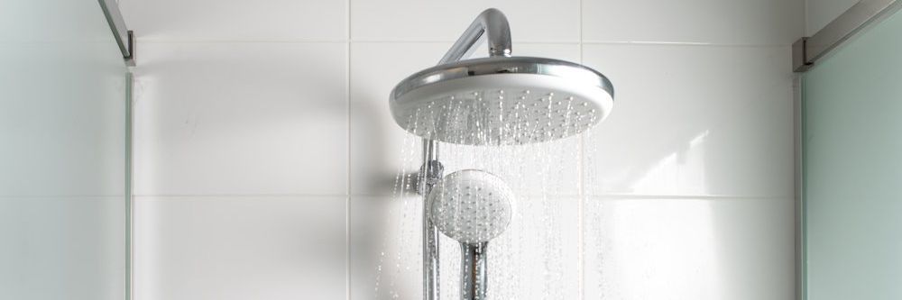 Ein verchromter Regenduschkopf, aus dem Wasser läuft.